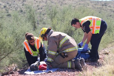Paramedics from AMR and a local firefighter work to stabilize a "patient" during the MVA drill hosted by Oracle Fire Department.