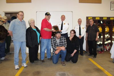 Assistant Chief Robert Jennings presents a plaque to Don Hartman's family.