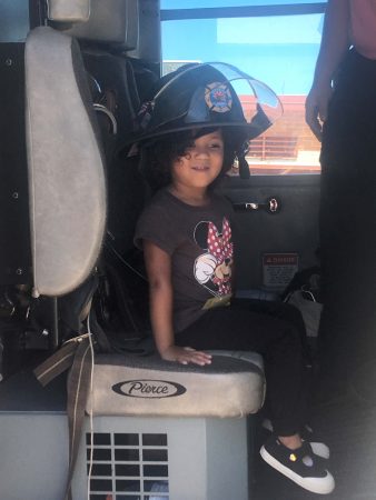 A young firefighter shows off her helmet.