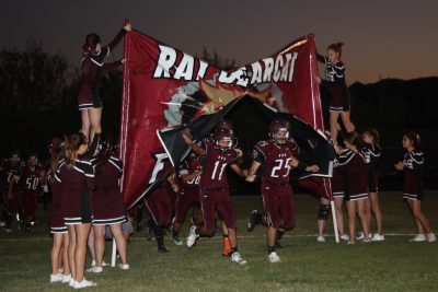 Tino Barragan (#11) and Fabian Valenzuela (#25) charge through the banner at Friday night’s non-game. Ray Cheerleaders hold the banner. 