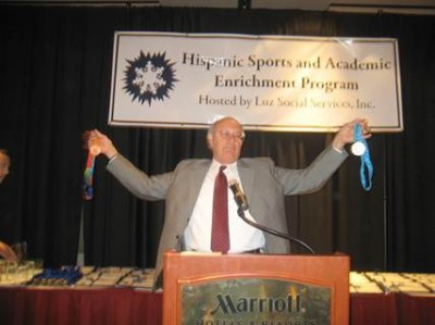 Beaming with pride, Dr. Barrón holds the two Olympic Medals earned by U.S. Women’s Water Polo Captain Brenda Villa, 2008 Keynote Speaker Hispanic Sports & Academic Enrichment Program
